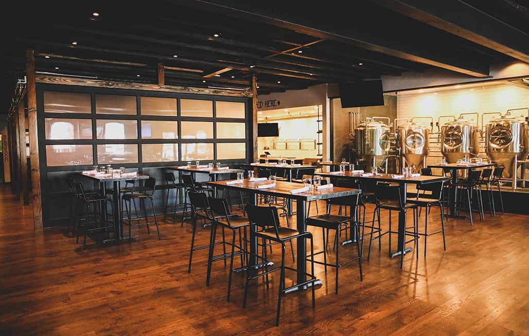 Empty dining room tables with with beer tanks and taps in the background at Roadhouse Pub & Eatery in Jackson, Wyoming.